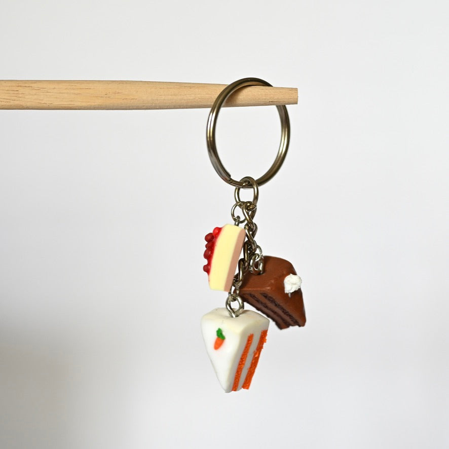 Handgemachter Schlüsselanhänger aus Polymer Ton, Metallring mit drei Kuchenstücken Motiv daran.