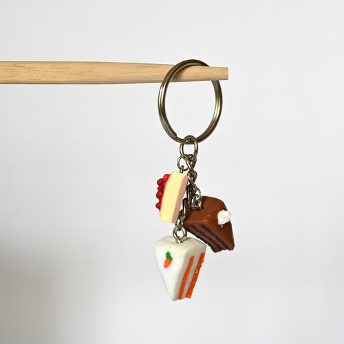 Handgemachter Schlüsselanhänger aus Polymer Ton, Metallring mit drei Kuchenstücken Motiv daran.